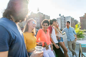 A group of people are standing on a balcony with a cityscape in the background.