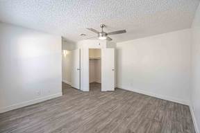 A room with a ceiling fan and wood flooring.