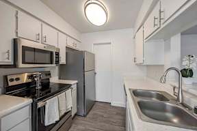A kitchen with a stove, oven, microwave, refrigerator, and sink.