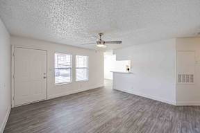 A room with a ceiling fan and wooden flooring.