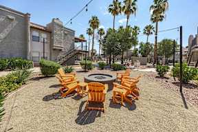 A patio with a fire pit and chairs.