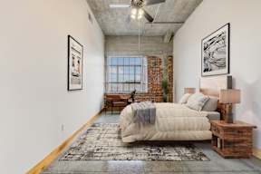 A bedroom with a large bed and a rug on the floor.