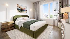 A bedroom with a green bed and a white nightstand.