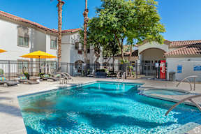 A pool with a yellow umbrella and palm trees in the background.