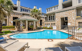 A swimming pool surrounded by lounge chairs and buildings.