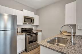 A kitchen with a stainless steel refrigerator, microwave, oven, and sink.