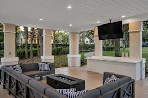 A modern outdoor living room with a television and comfortable seating.