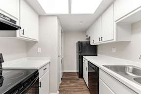 A kitchen with black appliances and white cabinets.