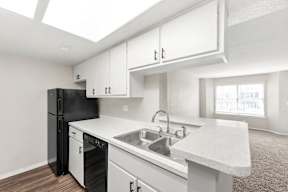 A kitchen with white cabinets and a black refrigerator.