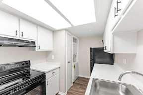 A kitchen with white cabinets and a black stove top oven.