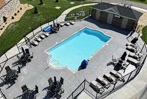 A small pool surrounded by a black fence and chairs.