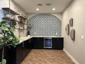a kitchen with black cabinets and a tile wall and a wood floor