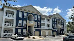 A white car is parked in front of a blue and white building.