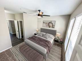 A bedroom with a bed, a ceiling fan, and a rug.