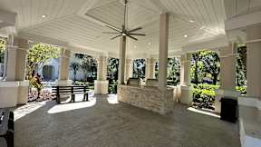 A covered patio with a ceiling fan and a stone pillar.