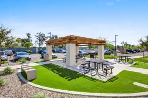 Downtown Phoenix, AZ Apartments - Imperial - Outdoor Community BBQ Area with Picnic Tables and a Grill Under a Pergola