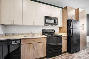 Apartments for Rent in Downtown Phoenix, AZ - Imperial - Kitchen with Wood-Style Flooring, Black Appliances, Granite-Style Countertops, and Light Wood-Style Cabinetry
