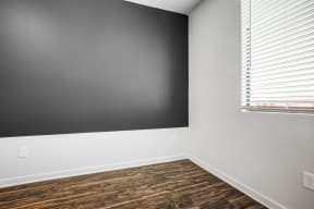 Central City Phoenix, AZ Apartments - Imperial - Bedroom with Wood-Style Flooring, a Black Accent Wall, and a Large Window