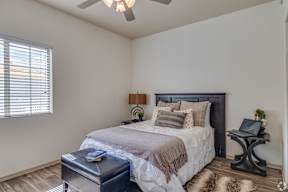 A bedroom with a bed, nightstand, and window with blinds.