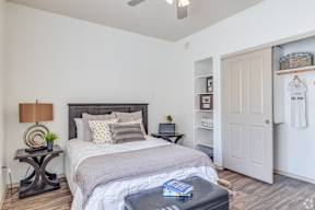 A bedroom with a bed, nightstand, and a small table with a plant on it.