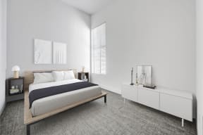 One Bedroom Apartments in North Hollywood CA - Lofts at NoHo Commons - Large Bedroom with Bed, Window, High Ceilings, Textured Flooring, Nightstands, Dresser Cabinet, and Wall Art