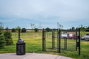 A black fence surrounds a trash can in front of a sign.