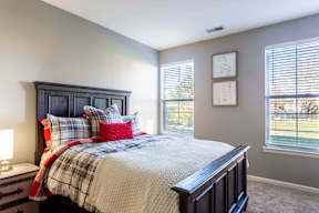 A bedroom with a bed, nightstand, and window.