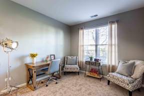 A room with a desk, chairs, and a window.