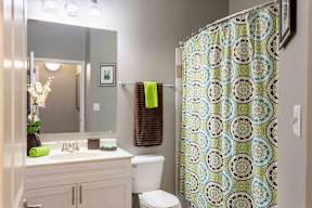 A bathroom with a toilet, sink, and shower curtain.