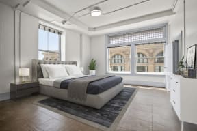 Apartments Downtown LA CA for Rent - Santa Fe Lofts - Large Bedroom with Bed, Nightstands, Lamp, Dresser, and Floor-to-Ceiling Windows.