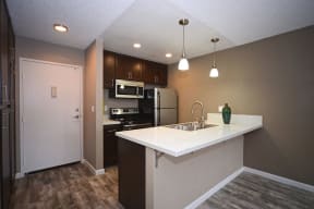 Apartments Near Cal State Northridge - Waterstone - Kitchen with Dark Wood Cabinetry, Granite Quartz Countertops, and Stainless Steel Appliances