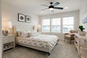 A bedroom with a large bed and a ceiling fan.