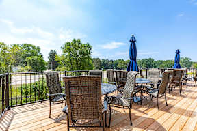 A wooden deck with chairs and tables is set up for outdoor dining.