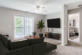 A living room with a green couch, a flat screen TV, and a ceiling fan.