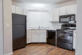an empty kitchen with black appliances and white cabinets