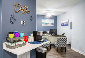 an office with a desk and chairs and a coffee bar with a computer