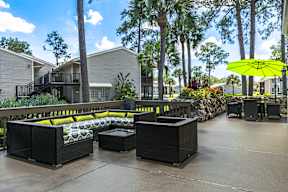 A patio with a yellow umbrella and black furniture.