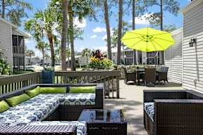 A patio with a yellow umbrella and a blue and white couch.
