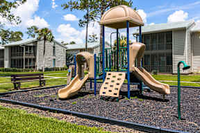A playground with a slide and a green pole.