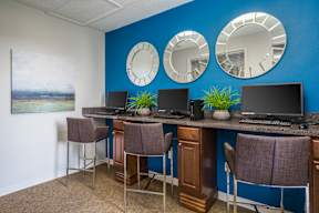 A room with a blue wall and a desk with three laptops on it.