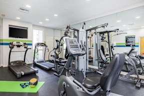 A gym with a variety of equipment including treadmills, stationary bikes, and weight machines.