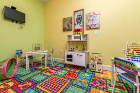 A child's playroom with a colorful rug and toys.