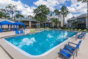 A large swimming pool with blue chairs and a white fence.