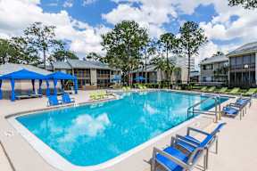 A large swimming pool with blue loungers and umbrellas.