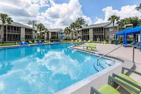 A large swimming pool with blue water and lounge chairs.