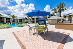 A patio with a table and chairs under a blue umbrella.