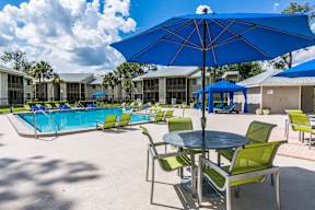 A blue umbrella is in the middle of a table and chairs.