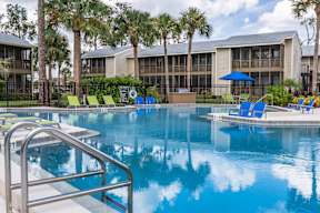 A swimming pool with a metal ladder and a blue umbrella.