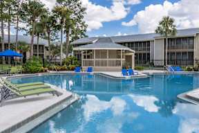 A swimming pool with a sun lounger and a building in the background.