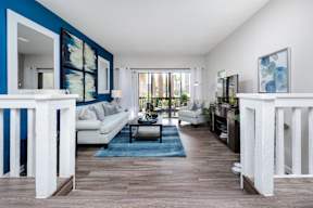 A living room with a white couch and a blue rug.